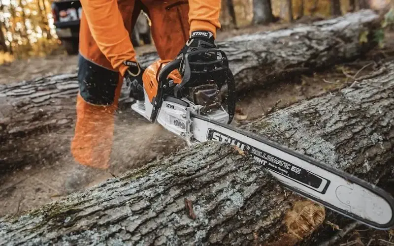 Άνδρας με φόρμα STIHL κόβει δέντρο με αλυσοπρίονο – Κατηγορία Πριόνισμα & Κοπή